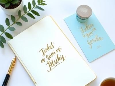 Kalligráfiai mottó íróasztalon, jegyzetfüzet és tollal